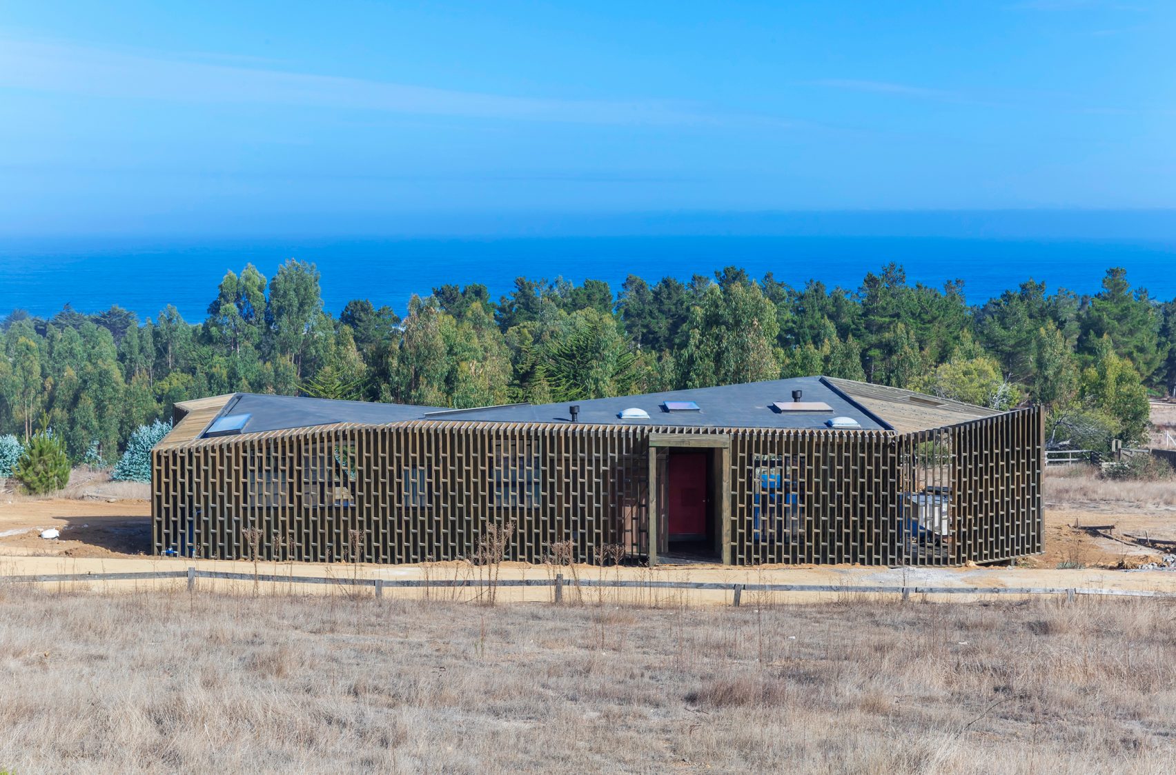 This beach house wrapped in a pavilion of slatted pine wood is located on a privileged western slope of the coastal mountain range in Punta de Lobos, Chile and presents amazing views of the South Pacific. Designed by LAND Arquitectos, the idea of the house is to optimize the views of the sea, maximize northern sunlight and offer protection from the south wind.